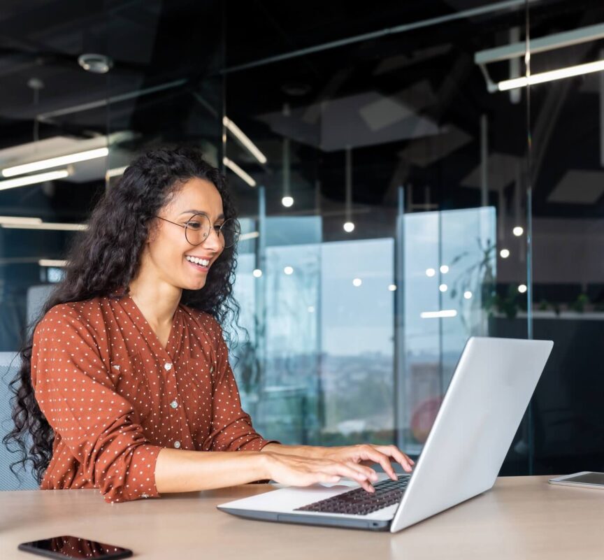 Someone sitting at an office desk using a laptop